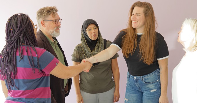 Handslag mellan kollegor på ett projektmöte på kontoret där projektgruppen består av personer med olika ålder och etnicitet
