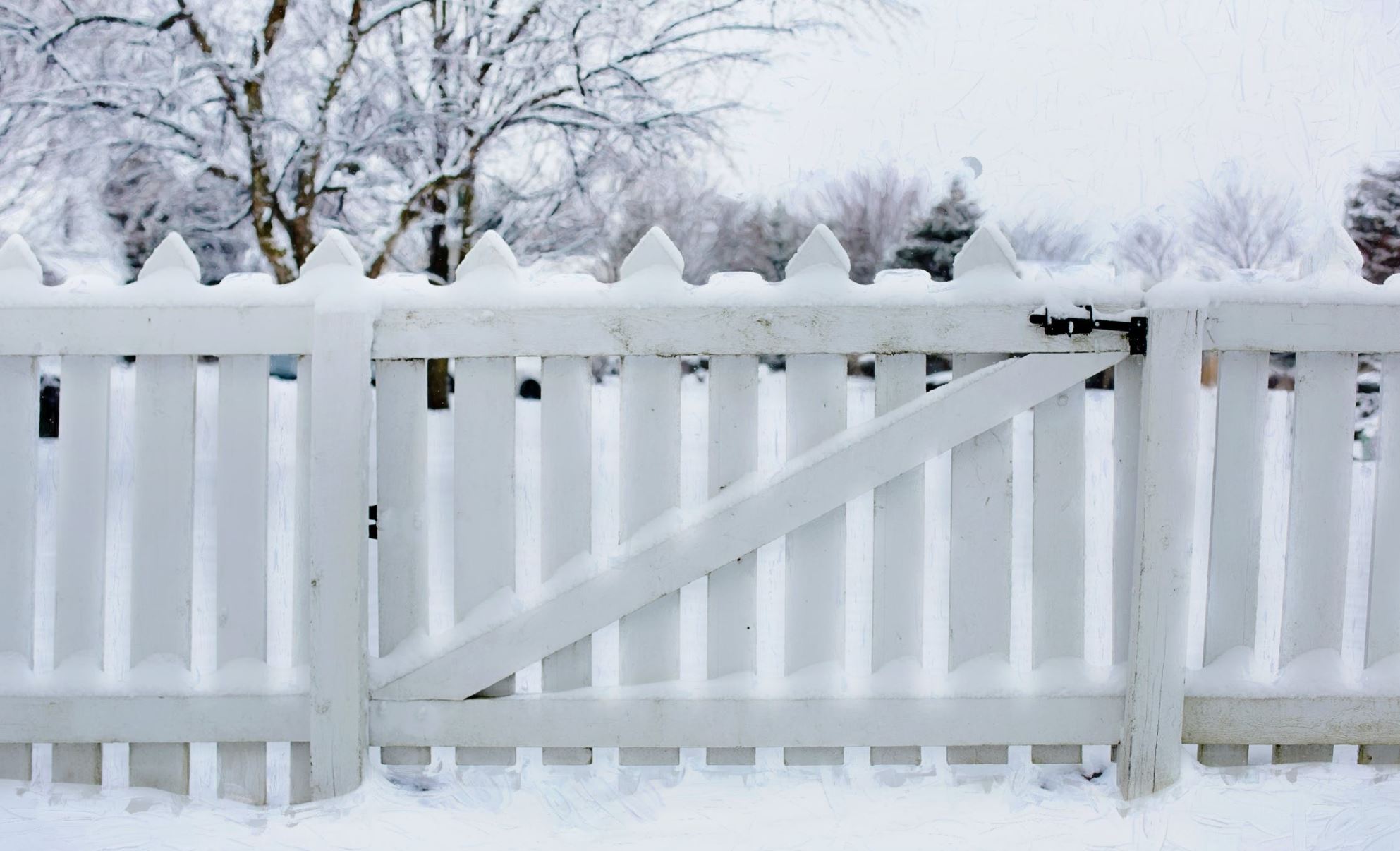 Snö på vitt staket och omkringliggande tomt och gångbana.